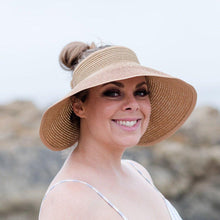 Load image into Gallery viewer, Model is wearing a tan bow visor with her brown hair in a bun. She has on a white swimsuit top and there are rocks and ocean in the background