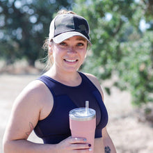 Load image into Gallery viewer, Model is wearing a camo hat front view and holding a pink cup.  She has on a black tank top and trees are in the background.