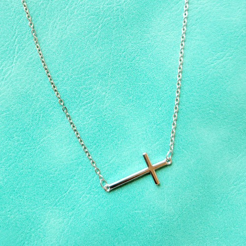 Slanted Cross Sterling Silver Necklace on a blue background. 