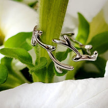 Load image into Gallery viewer, Picture of Leaf Adjustable Sterling Silver Ring wrapped around a stem with white flowers in the background