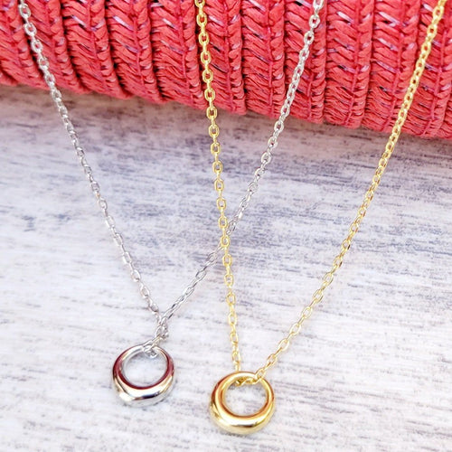  Silver and Gold Geometric Charm Necklaces on a grey surface with a red mesh background. 
