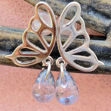 Load image into Gallery viewer, Picture of  Blue Stone Hollow Butterfly Sterling Silver Earrins on a brown and tan metal bar with a pink background.