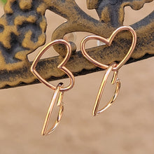 Load image into Gallery viewer, Asymmetrical double heart Sterling silver earring rose gold color on brown post with tan background.
