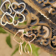 Load image into Gallery viewer, Asymmetrical double heart Sterling silver earring silver color on top and  rose gold color on bottom.  Both on a brown post with tan background.