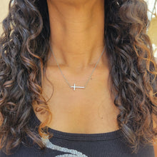 Load image into Gallery viewer, Slanted Cross Sterling Silver Necklace on a model with brown curly hair and a black shirt.