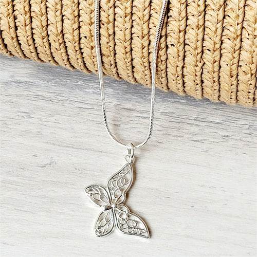 Slanted Butterfly Sterling Silver Necklace on a grey surface with tan mesh background. 