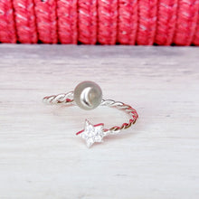 Load image into Gallery viewer, Picture of moonstone adjustable ring on a grey surface with a red background.