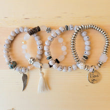 Load image into Gallery viewer, Cream Tasseled Beaded Layering Bracelet with all four bracelets laid out separately on a wood background.
