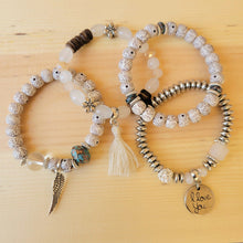 Load image into Gallery viewer, Cream Tasseled Beaded Layering Bracelet with all four bracelets laid out separately on a wood background.