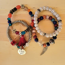 Load image into Gallery viewer, Rainbow Tasseled Beaded Layering Bracelet with all four bracelets laid out separately on a wood background.