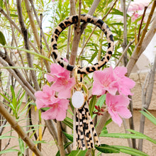 Load image into Gallery viewer, Leopard Print Key Ring Bracelet hanging on a tree with pink flowers and leaves in the background.