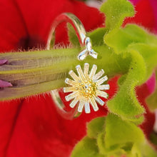 Load image into Gallery viewer, Picture of adjustable daisy ring wrapped around a green flower stem with red flowers in the back