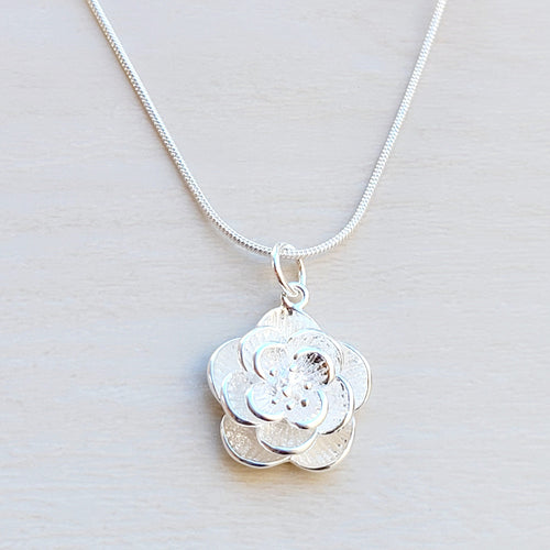 Picture of Flower Sterling Silver Necklace on a tan background 