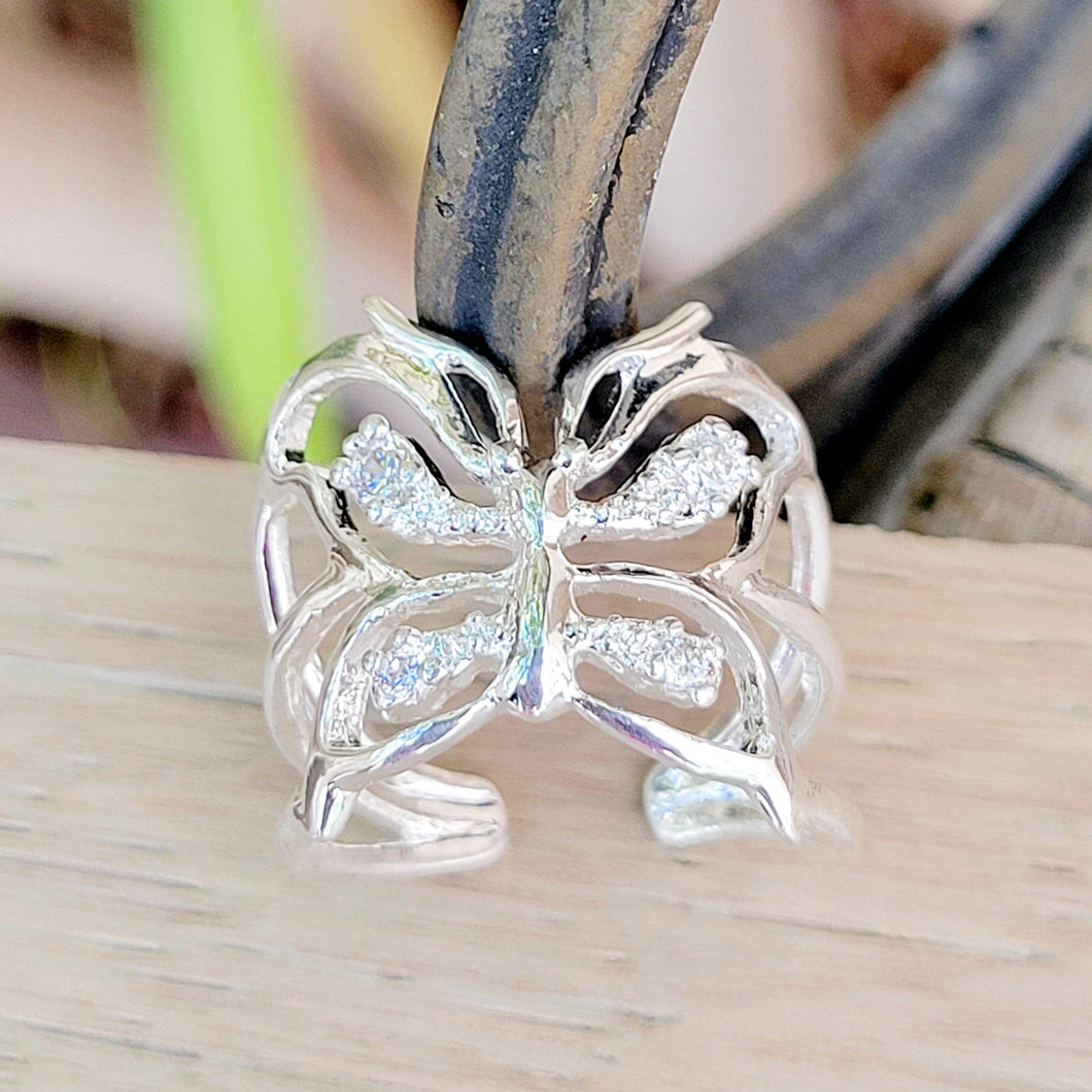 Adjustable butterfly ring on a tan background.  Metal  wire in the background.  