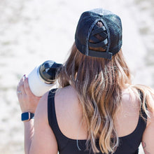 Load image into Gallery viewer, Black hat on model from the back.  Her hair is down, and she is wearing a black watch, black tank top, and holding a white water bottle
