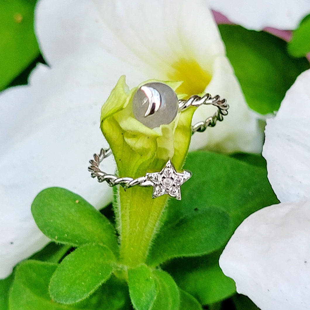 Picture of moonstone adjustable ring on a green stem with white flowers.