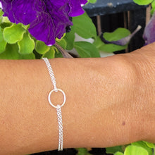 Load image into Gallery viewer, Double Strand Circle Sterling Silver Bracelet on a model&#39;s wrist with purple flowers and leaves in the background. 
