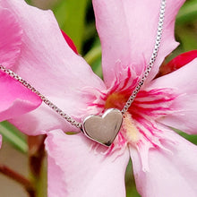 Load image into Gallery viewer, Elegant Heart Sterling Silver Necklace on a pink flower with green leaves in the background. 
