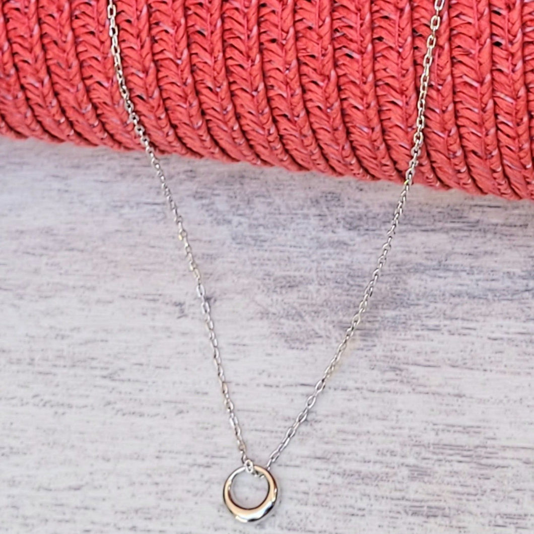 Silver Geometric Charm Necklaces on a grey surface with a red mesh background.