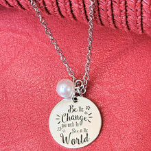 Load image into Gallery viewer, Picture of Be the Change You Wish to See in the World Inspirational Necklace with white charm with a red background. 
