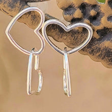 Load image into Gallery viewer, Asymmetrical double heart Sterling silver earring on brown post with tan background.
