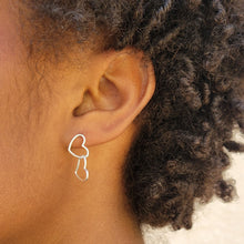 Load image into Gallery viewer, Asymmetrical double heart Sterling silver earring on model&#39;s left ear with the top heart in a vertical position. Model has short dark brown curly hair.
