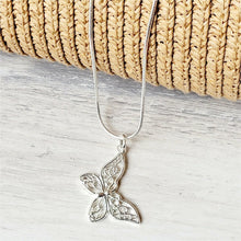 Load image into Gallery viewer, Slanted Butterfly Sterling Silver Necklace on a grey surface with tan mesh background. 
