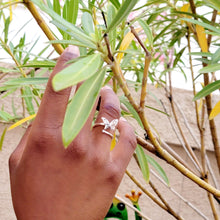 Load image into Gallery viewer, Picture of butterfly zircon adjustable sterling silver ring on model&#39;s right ring finger.   Model is holding branches with green leaves in the background. 
