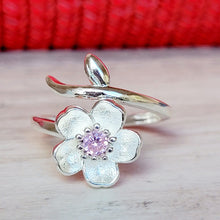 Load image into Gallery viewer, Picture of Plum Flower Adjustable Sterling Silver Ring on a grey surface with a red background.
