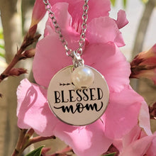 Load image into Gallery viewer, Picture of Blessed Mom Disc and Charm Necklace with white charm with pink flowers in the background.
