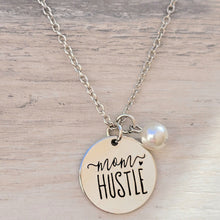 Load image into Gallery viewer, Mom Hustle Disc and Charm Necklace with a grey background. 
