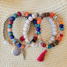 Load image into Gallery viewer, Rainbow Tasseled Beaded Layering Bracelet with all four bracelets laid out separately on a tan mesh background.
