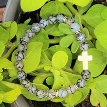 Load image into Gallery viewer, Silver Accent Beaded Cross Bracelet Grey on a leaves.
